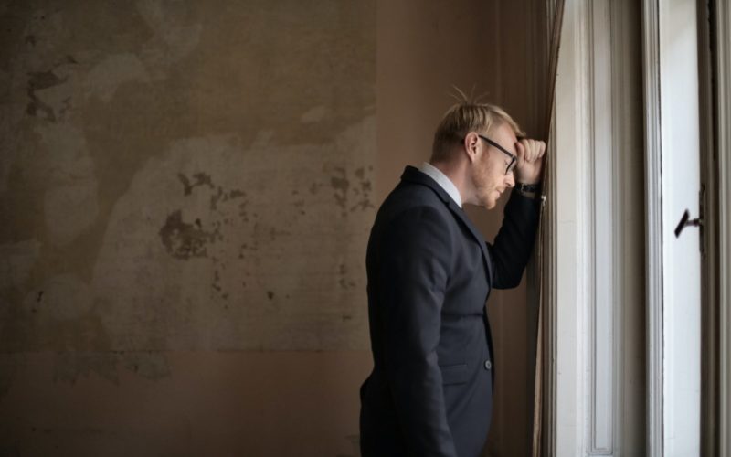 frustrated guy leaning his head on a wall
